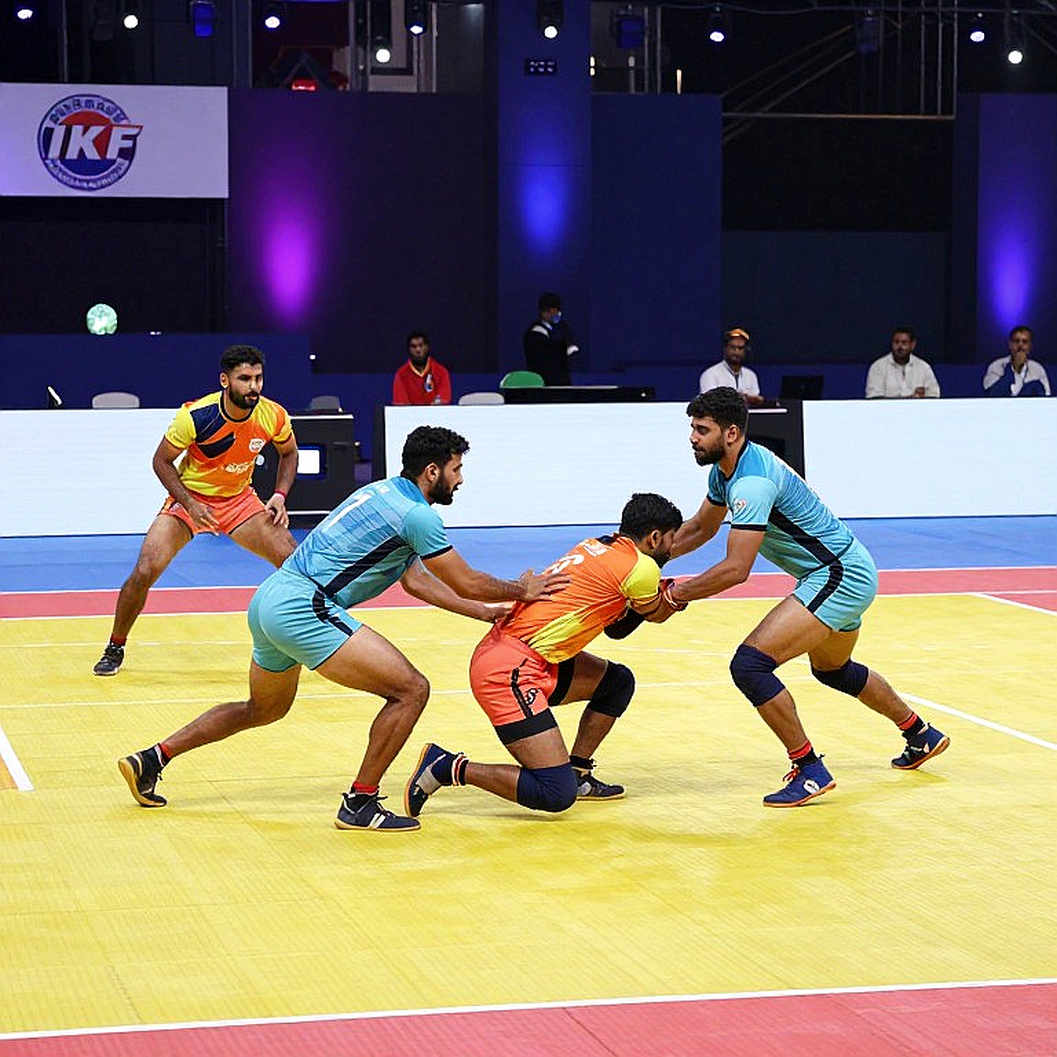 কমনওয়েলথ কাবাডি চ্যাম্পিয়নশিপ ২০২৬-এর লোগো: এক রেইডার, চার ডিফেন্ডার আর একটা অপঠিত ঘড়ি